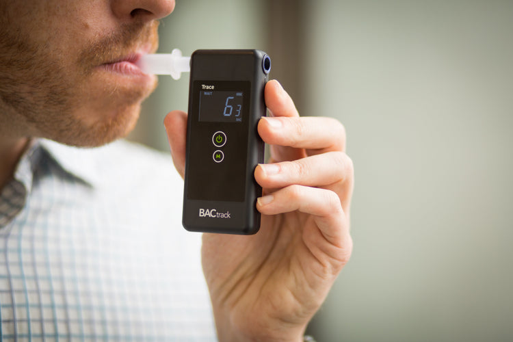 Man in a collared shirt blowing into a breathalyzer